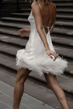 a woman in a white dress is walking down the street