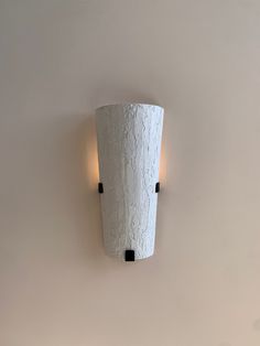 a white wall light mounted to the side of a wall