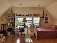 a bedroom with a bed, desk and chair in it's center area next to a window