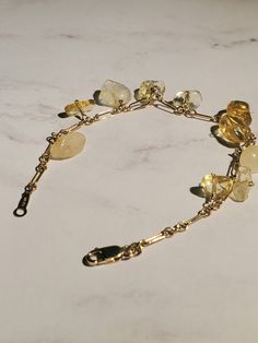 This simply beautiful bracelet is made with 14k gold filled long and small link chain (2×7mm) with genuine wire wrapped Citrine quartz nugget beads and finished with 14k gold filled lobster clasp (3×8mm) and quality tag (2×8mm). It looks beautiful alone or layering with other bracelets. Perfect gift for someone special or yourself. 14k Gold Filled Gemstone Bracelets, 14k Gold-filled Gemstone Bracelets, Gold Gemstone Bracelet In 14k Gold Filled, Gold Hand Wrapped Spiritual Crystal Bracelet, Gold Briolette Bracelets With Natural Stones, Gold Hand Wrapped Dangle Jewelry, Gold Hand-wrapped Dangle Jewelry, Gold Citrine Gemstone Bracelets, Spiritual Gold Gemstone Charm Bracelet