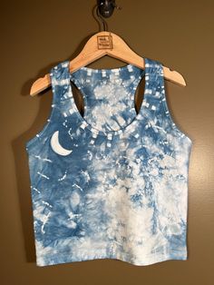 a blue and white tie dye crop top hanging on a hanger next to a brown wall