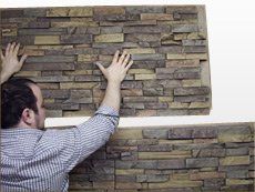 a man is reaching up against a wall made out of stacked stone blocks with his hands