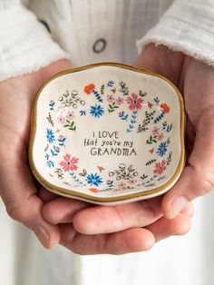 a person holding a small bowl in their hands with the words love, happiness, and grandma written on it