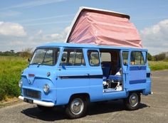 an old blue van is parked on the side of the road with its doors open