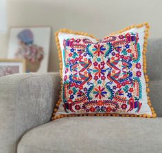 a decorative pillow with pom - poms sits on a couch in the living room