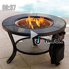 a fire pit sitting on top of a table next to a swimming pool