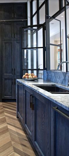 a kitchen with wooden floors and black cabinets