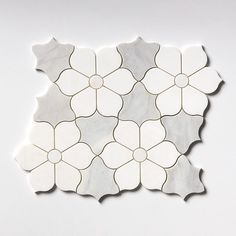 an image of a white tile design on the wall with flowers inlayed to it