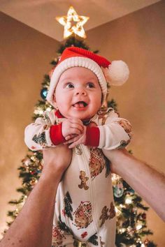 a man holding a baby in front of a christmas tree with a star on it