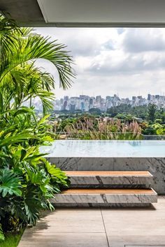 a bench sitting on top of a stone slab next to a lush green forest covered hillside