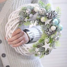 a woman holding a wreath with ornaments on it