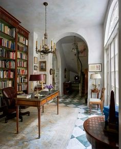 the room has many bookshelves and chairs in it, along with a chandelier