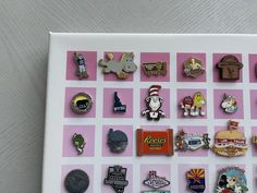 a bunch of pins sitting on top of a pink and white board next to each other