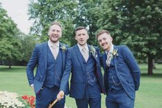 three men in blue suits standing next to each other