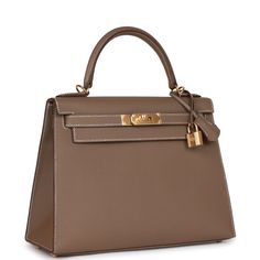 This Kelly, in the Sellier style, is in Etoupe epsom leather with gold hardware and has contrast stitching, front flap, two straps with center toggle closure, clochette with lock and two keys a single rolled handle and removable shoulder strap. The interior is lined with Etoupe chevre leather and has one zip pocket with an Hermes engraved pull and two open pockets on the opposite side. Collection: UOrigin: FranceCondition: Pristine; new or never (plastic on hardware)Accompanied by: Hermes box, H Hermes Etoupe, Visualization Board, Hermes Kelly Sellier, Kelly Sellier, Hermes Box, Togo Leather, Kelly Bag, Hermes Handbags, Hermes Bags