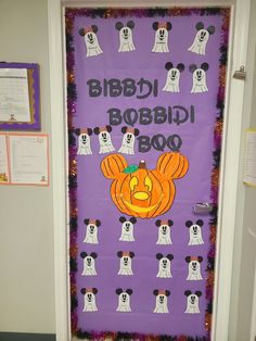 a door decorated for halloween with mickey mouse faces and pumpkins on it, in front of a purple background