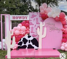 a pink and black cow themed birthday party with balloons on the wall, cactus decorations