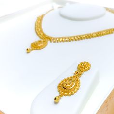 This gorgeous 22k gold necklace set, weighing 27.1 grams, features an elegant dangling design that adds a touch of dapper sophistication. The 16-inch necklace is crafted in radiant yellow gold, with a 1.25-inch drop and adjustable 1.5-inch links, secured by a reliable hook lock. Paired with matching 1.75-inch earrings, finished with secure screw-back posts, this set embodies refined luxury. Ideal for those who seek graceful elegance with a touch of movement, it’s perfect for elevating formal occ Luxury Gold-plated Gold Danglers, Luxury Yellow Gold Plated Chandbalis, Luxury Yellow Gold Kundan Pendant Necklace, Luxury Yellow Gold Chandbalis With Intricate Design, Luxury Yellow Jewelry For Puja, Luxury Yellow Gold Kundan Necklaces, Luxury Traditional Yellow Temple Necklace, Luxury Kundan Jewelry In Yellow Gold, Luxury Yellow Gold Necklace For Puja