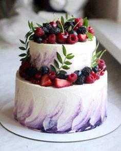 a three tiered cake with berries and leaves on top