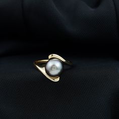 a close up of a ring with a pearl on it