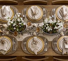 the table is set with white and gold place settings, silverware, and flowers