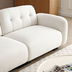 a white couch sitting on top of a hard wood floor next to a wooden table