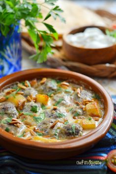 a bowl of soup with meat and vegetables in it on a table next to some bread