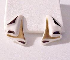 Black white satin enamel accented porcelain waves clip on earrings vintage gold and silver tone metal finish large draped swirl polished ceramic discs. Vintage Avon styled fashion jewelry. In excellent never worn still in the original Avon box vintage condition. Measures 1 3/8 inches long 1 inch wide. Avon 1989 Porcelain Waves Clip On Earrings White Retro Earrings For Formal Occasions, Retro White Earrings For Formal Occasions, White Retro Formal Earrings, Vintage White Gold Clip-on Earrings, Vintage Clip-on White Gold Earrings, Retro Clip-on Hoop Earrings, Vintage Enamel Clip-on Earrings, Short Hills, Avon Fashion