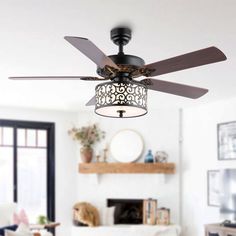 a ceiling fan in a living room with white walls and furniture, including a fireplace