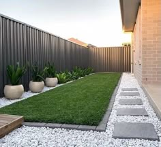 a backyard with grass and stepping stones on the ground, next to a fenced in area