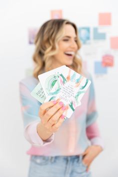 a woman holding up some money in front of her face and smiling at the camera