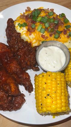 a white plate topped with corn, potatoes and other foods on top of a wooden table