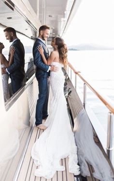 a bride and groom standing on the deck of a boat