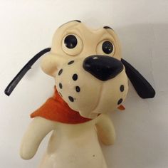 a toy dog with big eyes and a scarf around it's neck on a white surface