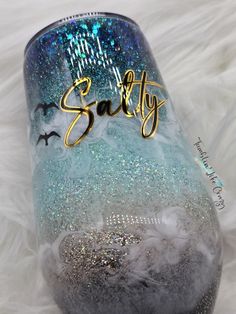 a wine glass with the word salty painted on it sitting on a white furnishing