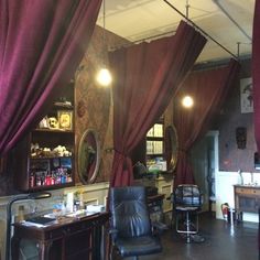 the interior of a barbershop with red curtains