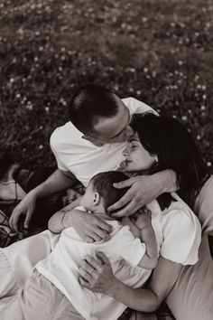 a man and woman holding a baby in their arms while sitting next to each other