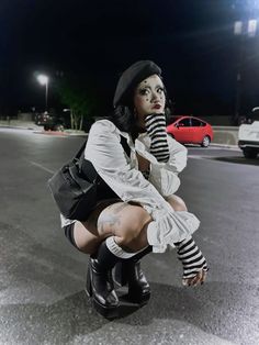 a woman kneeling down in the middle of a parking lot with her hand on her mouth