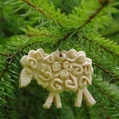 a sheep ornament hanging from a tree branch with green needles in the foreground