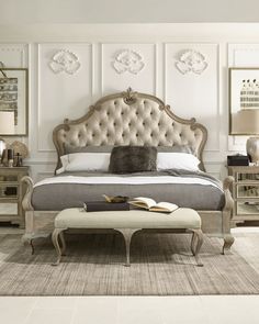 a bedroom with a bed, dressers and an ottoman on the floor in front of it