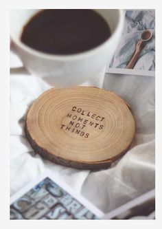 a wooden coaster with the words collect moments and things on it next to a cup of coffee