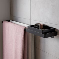 a towel rack with a watch on it next to a window sill and pink towels