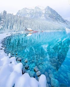 the water is crystal blue and there are rocks on the shore in front of it