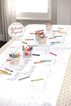 pencils are lined up on a table with paper cups and crayons in them