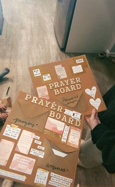 a person sitting on the floor holding up a paper board with words and notes attached to it