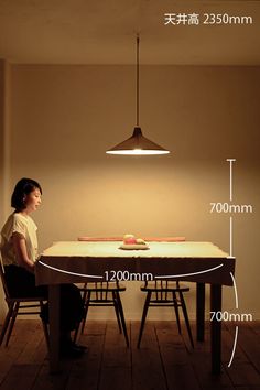 a person sitting at a table in front of a light that is on the wall