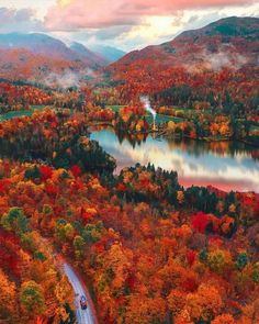 an aerial view of a lake surrounded by trees in the fall with colorful foliage around it