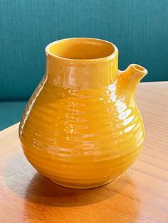 a yellow vase sitting on top of a wooden table