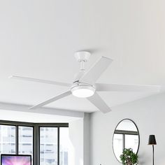 a white ceiling fan in a living room next to a desk with a computer on it