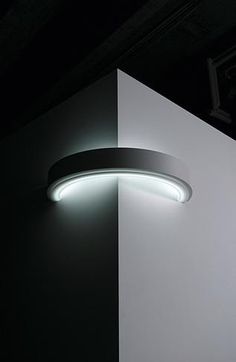 a black and white photo of a light fixture on the side of a wall in a dark room